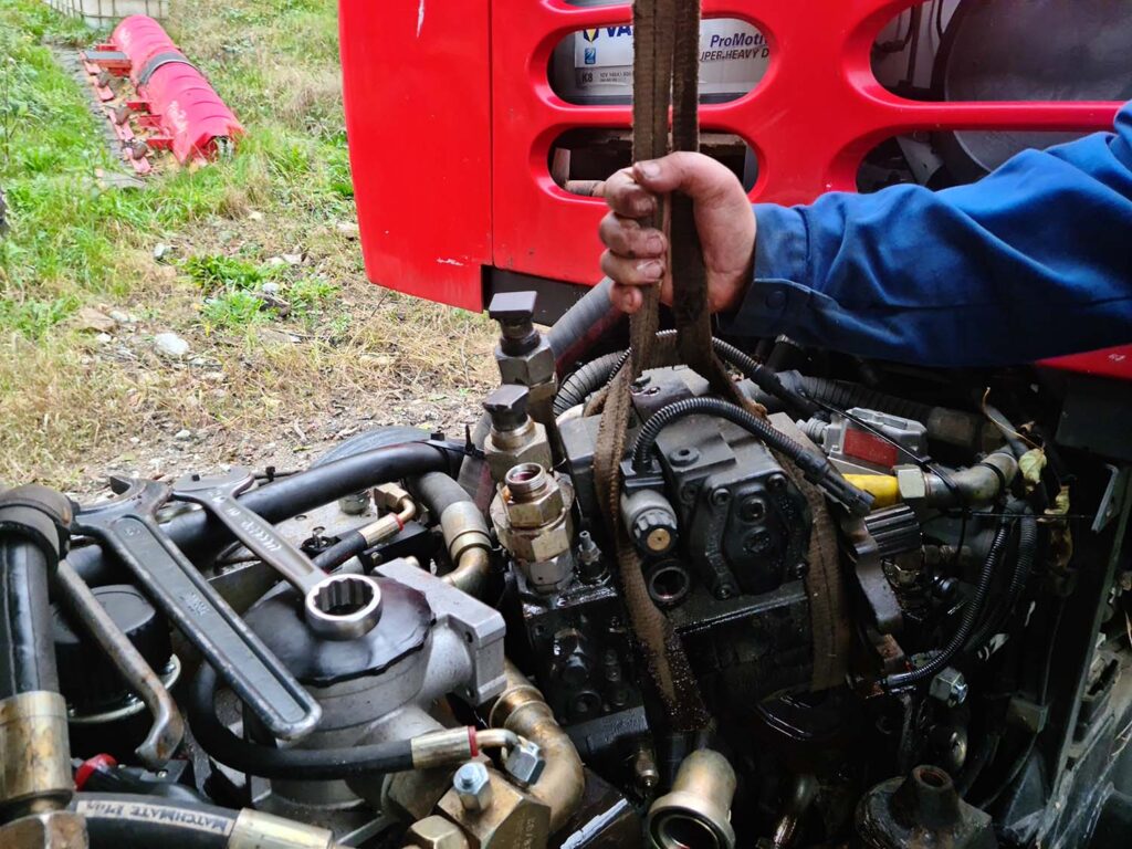 Photo de Gérald entrain de réaliser la maintenance d'une pompe hydraulique de dameuse dans la Alpes.